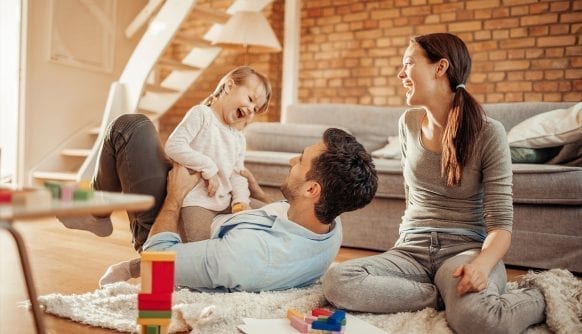 Vesela mlada porodica na podu dnevne sobe se igra sa malom cerkom